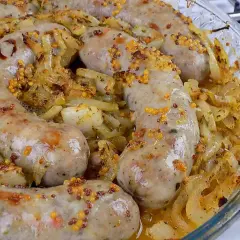 Pyszna biała kiełbasa pieczona w cebuli i musztardzie, z chrupiącymi ziarnami gorczycy. Aromatyczne danie w szklanej formie.