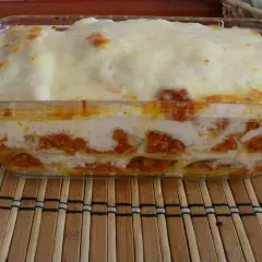 Pyszne cannelloni z mięsem mielonym, zapieczone pod warstwą sera i sosu, prezentują się apetycznie w szklanym naczyniu.
