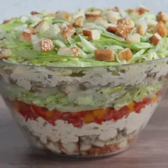 Warstwowa sałatka big mac w szklanej misie, z chrupiącymi grzankami na wierzchu.