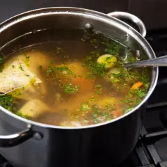 Garnek z bulionem, kawałkami kurczaka, warzywami i natką pietruszki. Idealny do nauki, jak zrobić rosół.