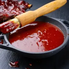 Pyszne żeberka w sosie bbq. Pędzel zanurzony w sosie, gotowy do posmarowania mięsa. Idealny sos bbq przepis na grilla.