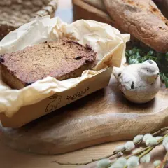 Domowy pasztet z królika w papierowej foremce, obok ceramiczny ptaszek i chleb.