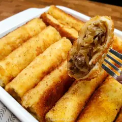 Chrupiące krokiety z kapustą i grzybami. Widać bogaty farsz do krokietów w jednym z nich, podniesionym na widelcu.