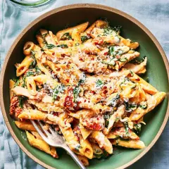 Penne w kremowym sosie ze szpinakiem i suszonymi pomidorami, posypane parmezanem i płatkami chili.