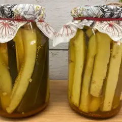Dwa słoiki z cukinią w zalewie słodko-kwaśnej z curry. W tle gałązka rozmarynu.