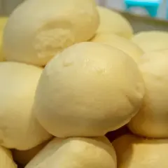 Stos puszystych, białych klusek na parze, gotowych do podania.