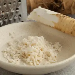 Start your culinary adventure: jak zrobić chrzan. Świeży korzeń chrzanu, tarka i miseczka z tartym chrzanem.