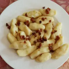 Kopytka z boczkiem, jak u babci! Pyszne ciasto na kopytka przepis babci, podane na białym talerzu.