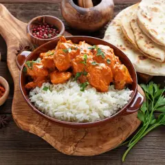 Pyszne chicken tikka masala z ryżem, podane z plackami naan i przyprawami.