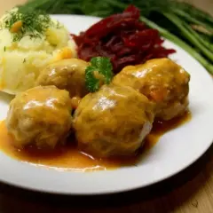 Pyszne klopsiki w sosie pomidorowym, podane z purée ziemniaczanym i buraczkami. Danie ozdobione natką pietruszki i koperkiem.