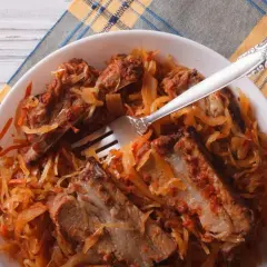 Pyszne żeberka w kapuście kiszonej, podane na talerzu z widelcem, gotowe do jedzenia.
