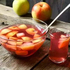 Szklanka i miska pełne pysznego, domowego kompotu z jabłek, obok świeże owoce.
