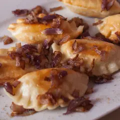 Pyszne pierogi z mięsem, posypane chrupiącą cebulką, kuszą swoim wyglądem.
