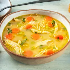 A miseczce paruje aromatyczna zupa z kurczakiem, pełna makaronu, marchewki i zielonej pietruszki. Idealna na chłodne dni.