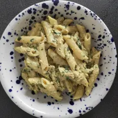 Penne z kremowym sosem, tuńczykiem i natką pietruszki w talerzu w granatowe cętki. Pyszny makaron z tuńczykiem.
