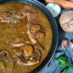 Pyszny strogonow ze schabu w sosie z cebulą i marchewką, gotowy do podania. Obok składniki: marchew, cebula, czosnek i bazylia.
