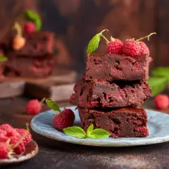Stos pysznych brownie z malinami, ozdobiony świeżymi malinami i listkami mięty.
