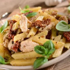 Penne z kurczakiem i suszonymi pomidorami, udekorowane świeżą bazylią. Pyszne danie, które zachwyci każdego smakosza.