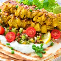 Pyszna shoarma z kurczaka na chlebku pita, z jogurtowym sosem, świeżymi warzywami i cytryną.