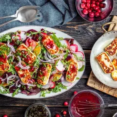 Kolorowa sałatka z grillowanym halloumi, burakami, pomarańczą i rukolą, polana sosem żurawinowym.