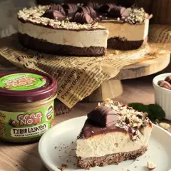 Pyszne ciasto Kinder Bueno z kremem i orzechami, obok słoik pasty z orzechów laskowych.