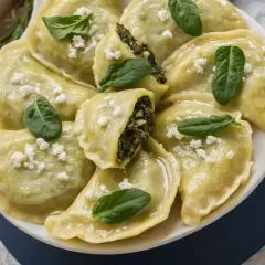 Pyszne pierogi ze szpinakiem i fetą, udekorowane świeżymi listkami szpinaku.