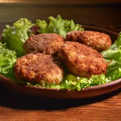 Cztery soczyste mielone z air fryer, podane na liściach sałaty, kuszą apetycznym wyglądem.