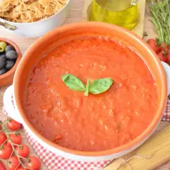 Pyszny, domowy makaron z sosem pomidorowym, przygotowany ze świeżych pomidorów, czosnku i bazylii. Obok składniki do dania: oliwki, kapary, makaron i zioła.