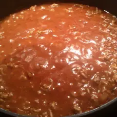 Gęsty, aromatyczny sos do spaghetti z mielonym mięsem, gotujący się w garnku.