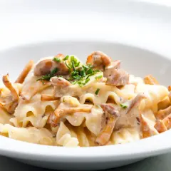 Pyszny makaron z kurkami w kremowym sosie, posypany świeżą natką pietruszki. Idealne danie dla miłośników grzybów.