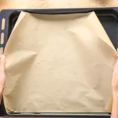 Dłonie układają papier do pieczenia na blasze. To świetne rozwiązanie, co zamiast papieru do pieczenia, gdy chcesz uniknąć przypalenia.