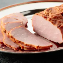 Pyszna, wędzona szynka na obiad, pokrojona w plastry na srebrnej tacy.