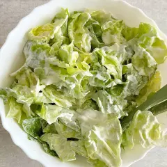 Chrupiąca sałata ze śmietaną, podana w białej misce. Idealna na lekki posiłek.