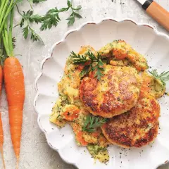Kotlety mielone z indyka podane z puree z marchewki i natką pietruszki. Obok leżą świeże marchewki.