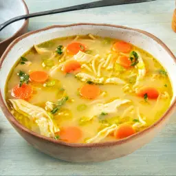 A miseczce paruje aromatyczna zupa z kurczakiem, pełna makaronu, marchewki i zielonej pietruszki. Idealna na chłodne dni.