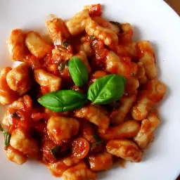 Pyszne gnocchi w sosie pomidorowym, udekorowane listkami bazylii. Idealne danie na szybki obiad.