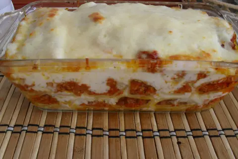 Pyszne cannelloni z mięsem mielonym, zapieczone pod warstwą sera i sosu, prezentują się apetycznie w szklanym naczyniu.