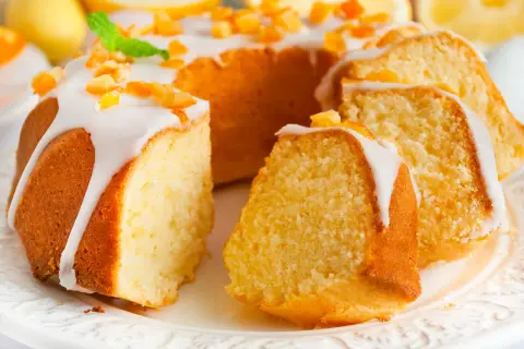 Puszysta babka wielkanocna cytrynowa, polana lukrem i posypana kandyzowaną skórką cytrynową, prezentuje się apetycznie.