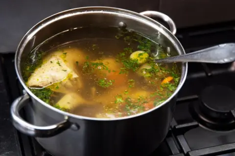 Garnek z bulionem, kawałkami kurczaka, warzywami i natką pietruszki. Idealny do nauki, jak zrobić rosół.