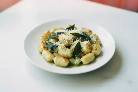 Pyszne gnocchi z sosem, posypane parmezanem i ozdobione listkami szałwii. Idealne danie dla miłośników włoskich smaków.