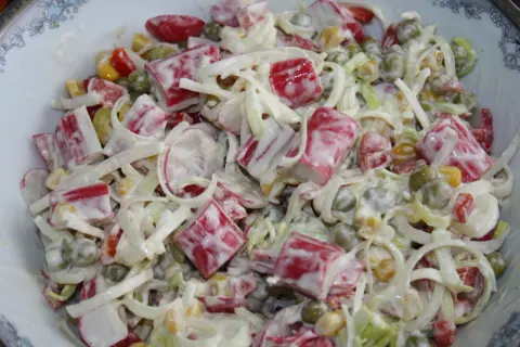 Pyszna sałatka z surimi, groszkiem, kukurydzą i porem, polana kremowym sosem.