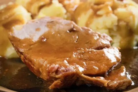 Soczysta karkówka w sosie własnym, podana z purée ziemniaczanym. Idealny obiad dla całej rodziny.
