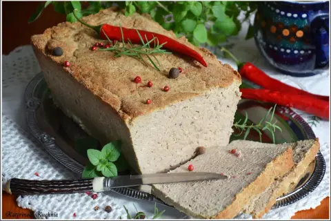 Pyszny pasztet mieszany drobiowo-wieprzowy, udekorowany papryczką chili i ziołami, gotowy do podania na kromkach chleba.