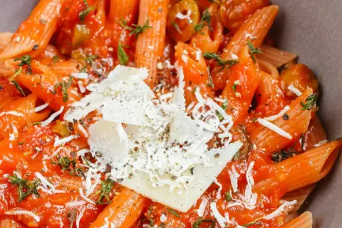 Penne w sosie pomidorowym z oliwkami i parmezanem, aromatyczne dania z makaronem.