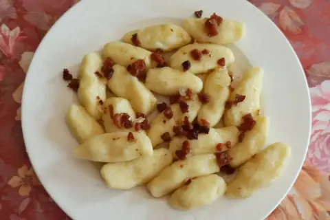 Kopytka z boczkiem, jak u babci! Pyszne ciasto na kopytka przepis babci, podane na białym talerzu.