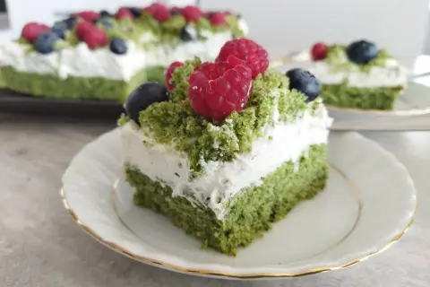 Zielony biszkopt przełożony kremem z mascarpone, ozdobiony malinami i borówkami. Pyszne ciasto leśny mech z mascarpone.