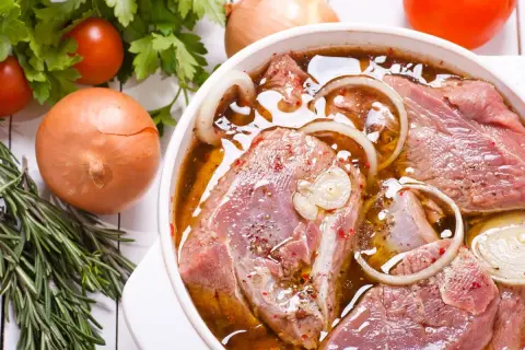 Kawałki indyka w aromatycznej marynacie z cebulą i ziołami, gotowe do pieczenia.