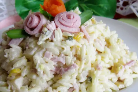 Pyszna sałatka z makaronem ryżowym, szynką i ogórkiem, udekorowana różyczkami z szynki i marchewki.