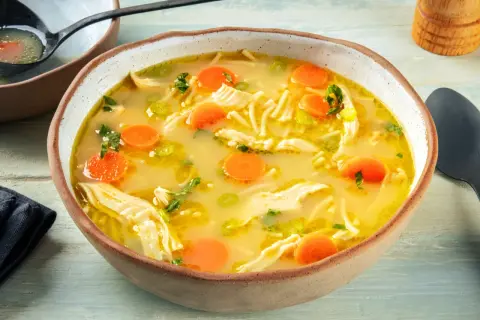 A miseczce paruje aromatyczna zupa z kurczakiem, pełna makaronu, marchewki i zielonej pietruszki. Idealna na chłodne dni.