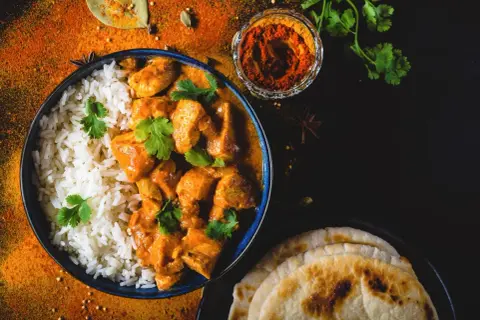 Aksamitny butter chicken przepis z ryżem i plackami naan. Aromatyczne przyprawy i świeża kolendra dopełniają danie.